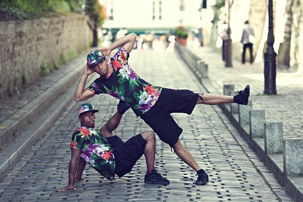 Deux danseurs de hip-hop réalisant une figure de breakdance dans une rue pavé